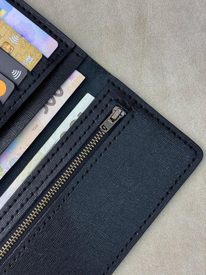 A close-up of an open black textured wallet showing card slots, cash compartments, and a zippered pocket, photographed on a neutral beige surface.