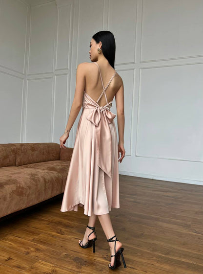 Woman in a pink dress standing in a room with wooden flooring and a brown sofa.
