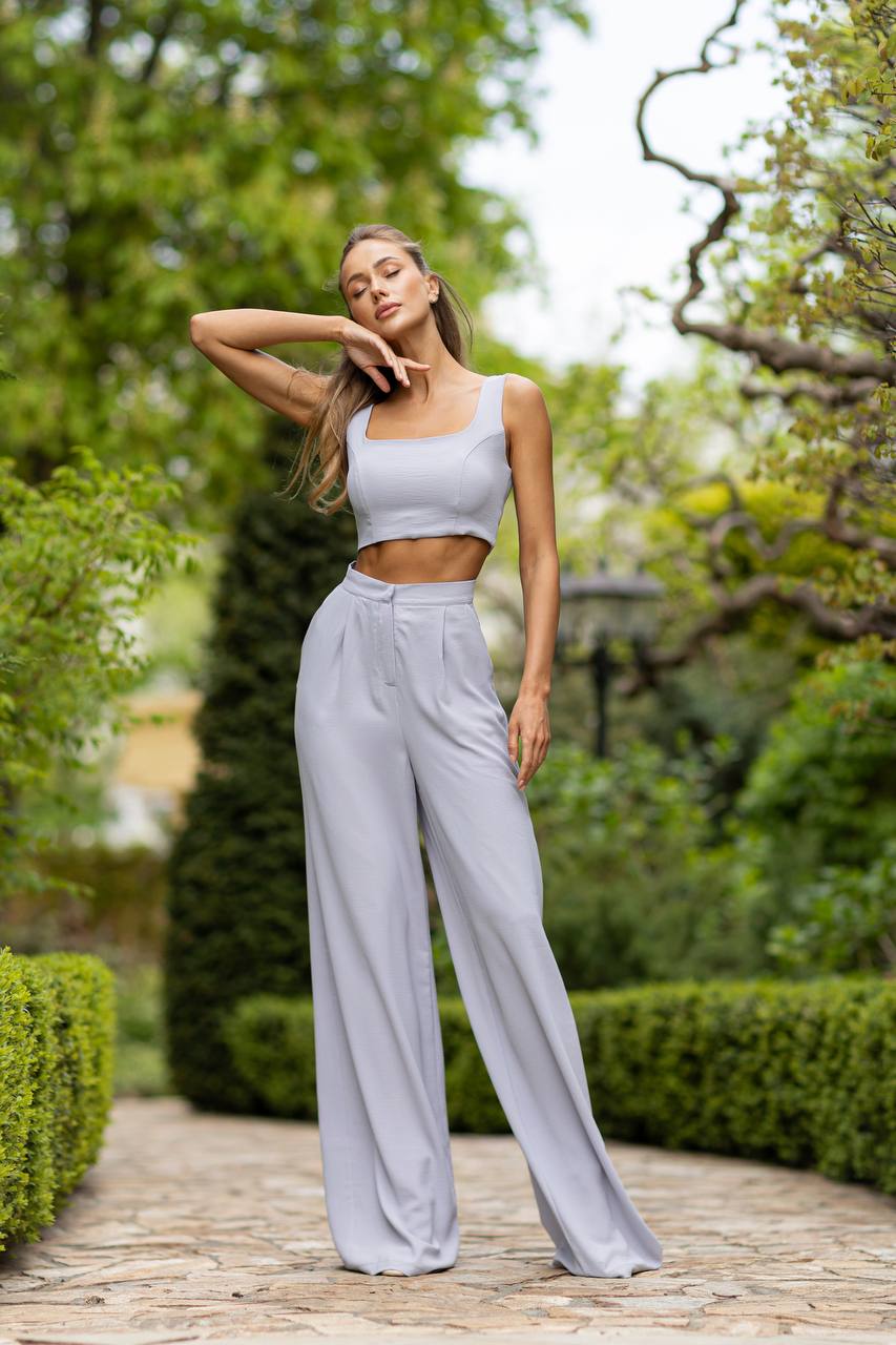 Woman in light gray outfit standing in a garden