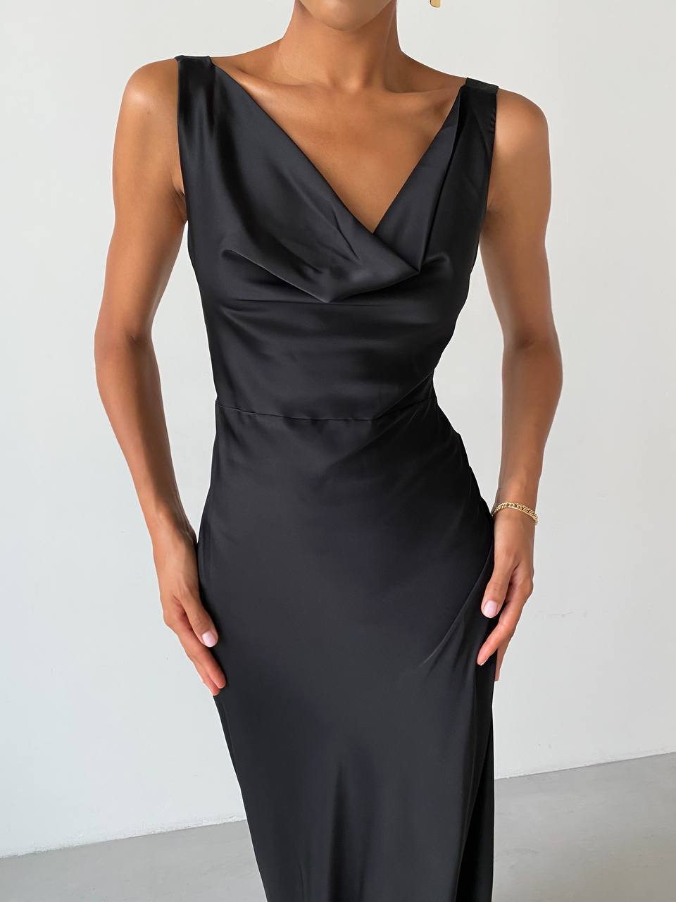Black evening gown with draped neckline on a plain background