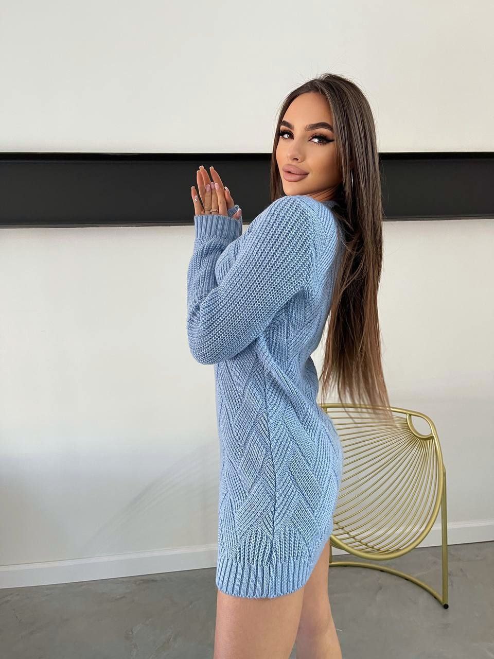 Woman wearing a light blue knitted dress in an indoor setting