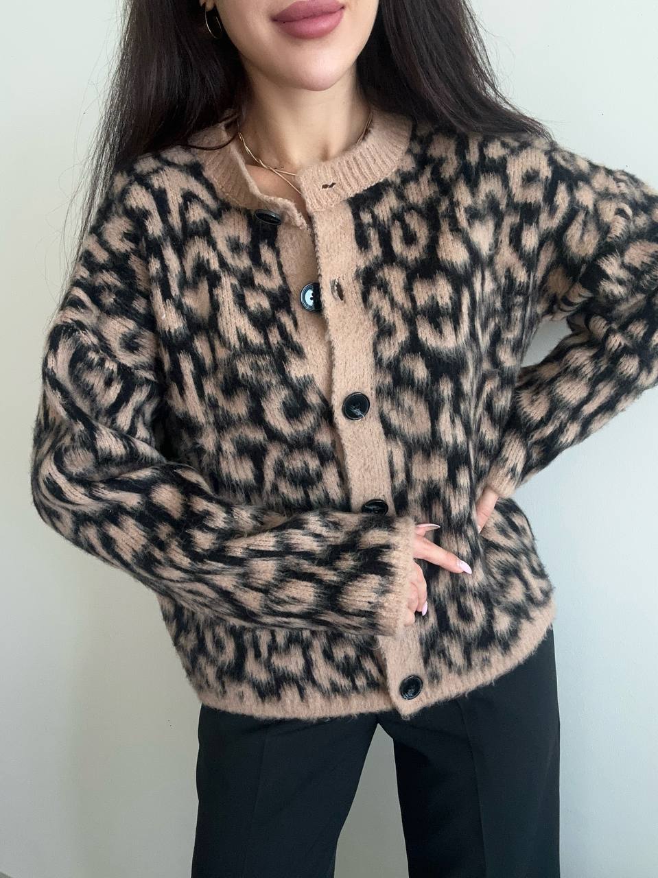 Person wearing a leopard print cardigan with a plain background