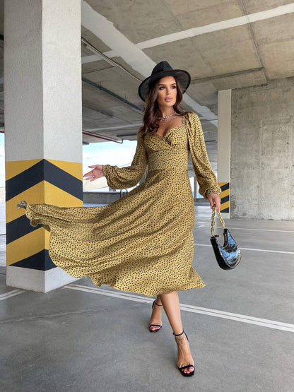 Woman in a yellow dress and black hat standing in an urban setting