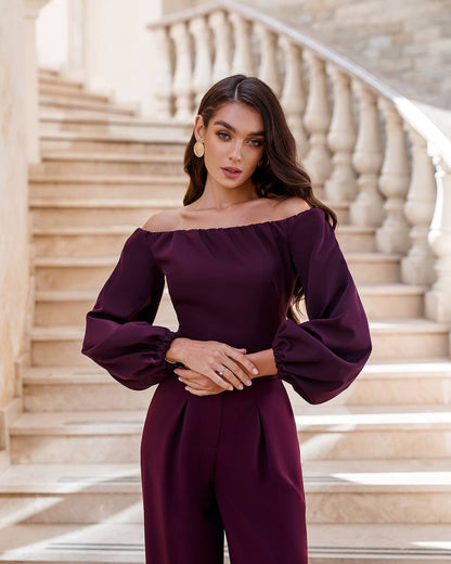 Woman wearing a purple off-shoulder outfit standing on a staircase.