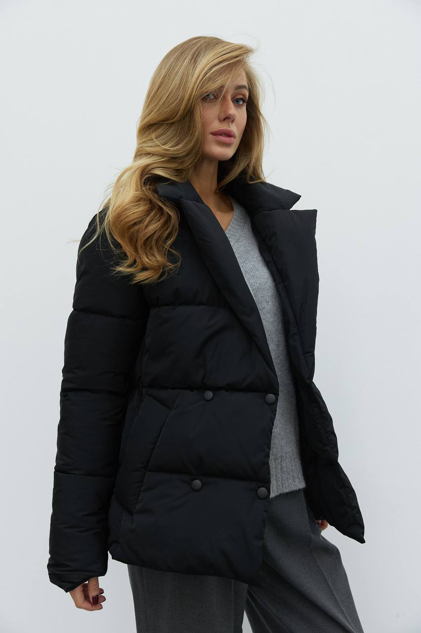 Woman wearing a black puffer jacket against a white background