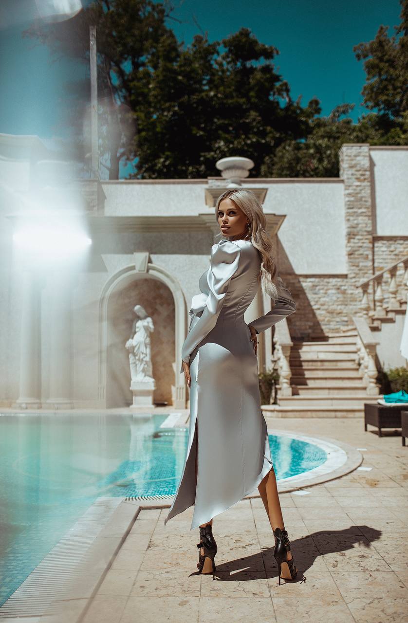 Woman in a white dress standing by a pool with a scenic background