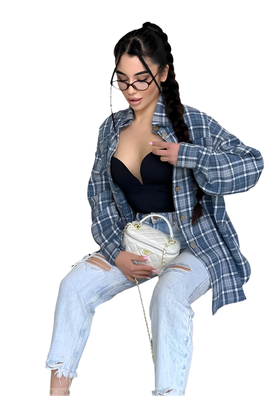 Woman wearing a blue plaid shirt over a black top and light blue jeans, sitting on a white background.