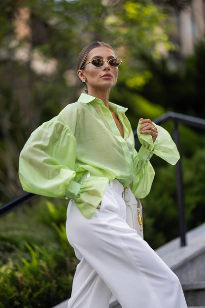 Woman wearing a bright green shirt and white pants outdoors