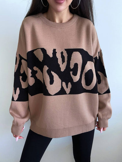 Beige sweater with black abstract pattern worn by a person against a white background