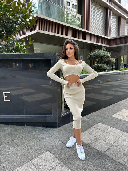 Woman in a white outfit standing on a sidewalk with modern buildings in the background