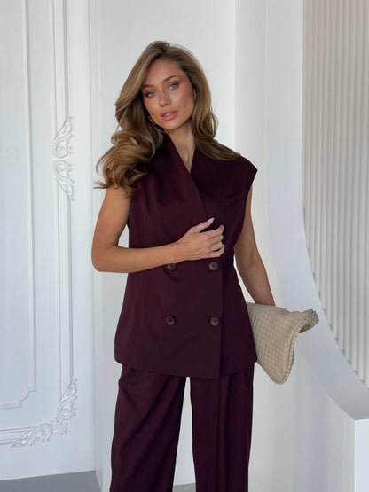 Woman wearing a burgundy suit with a white wall background