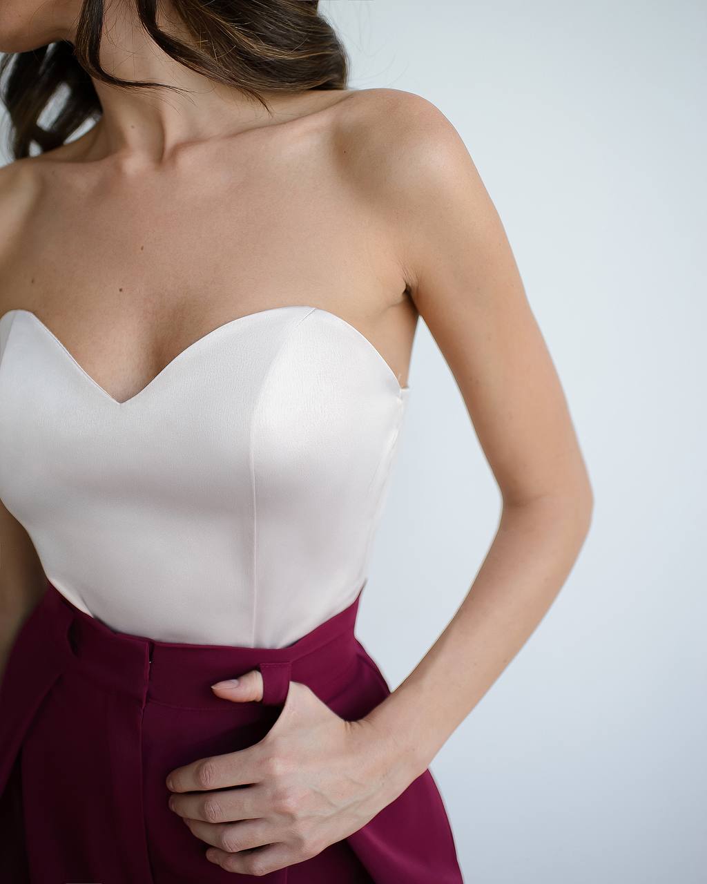 White strapless top and burgundy skirt worn by a person on a plain background