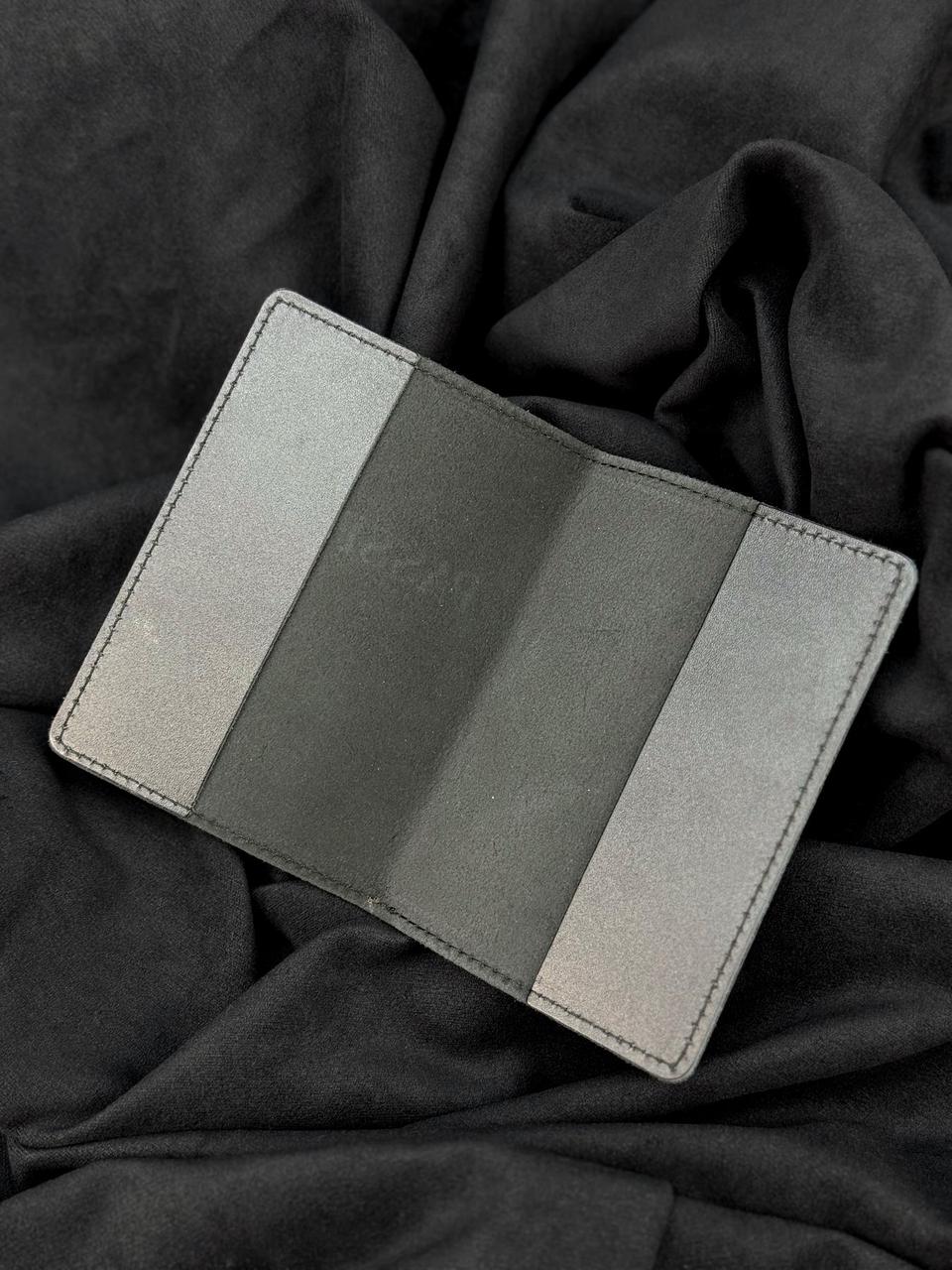 A slim, minimalist card holder or wallet with a three-panel color-blocked design in light gray, dark gray, and silver, displayed on a dark gray fabric background.