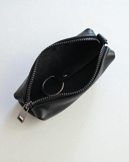A small black zippered pouch with a silver zipper pull and a metal key ring inside, shown open on a plain white background.