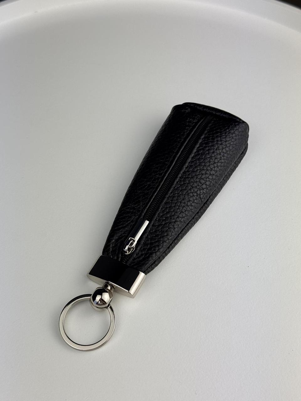 A black pebbled leather keychain pouch with a silver-tone metal zipper and key ring, shown on a plain white background.