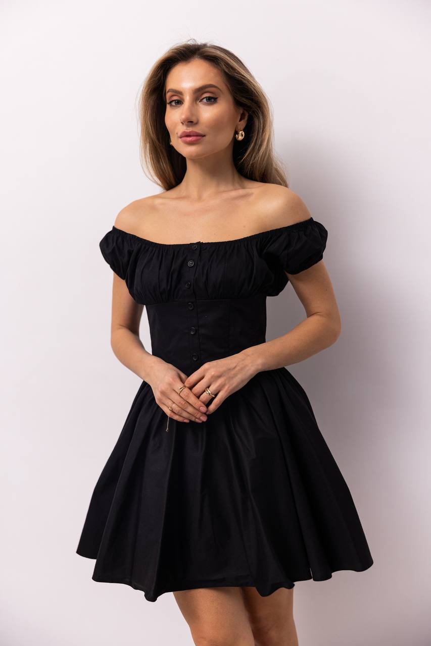 Woman wearing a black off-shoulder dress against a white background