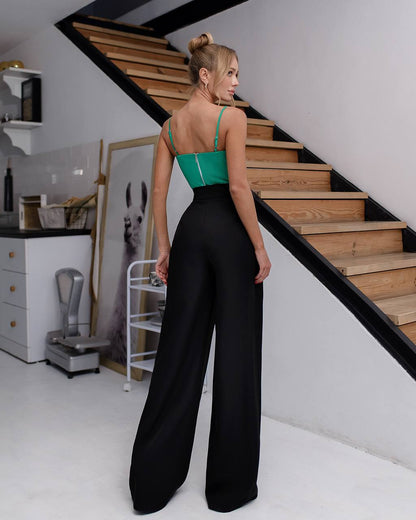 Woman in a green top and black pants standing on a staircase in a home setting