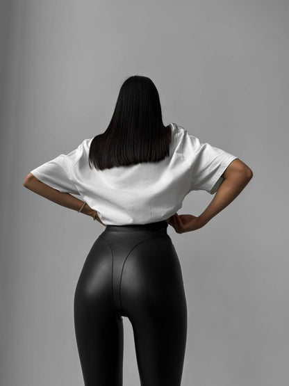 Person wearing a white shirt and black leggings against a gray background