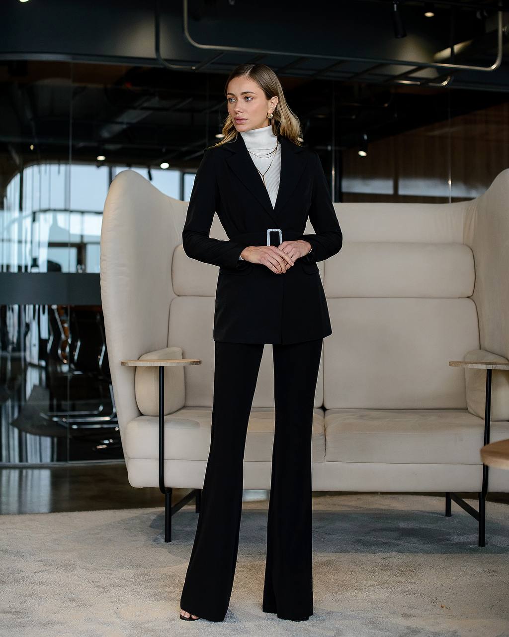 Woman in a black suit standing in a modern interior setting