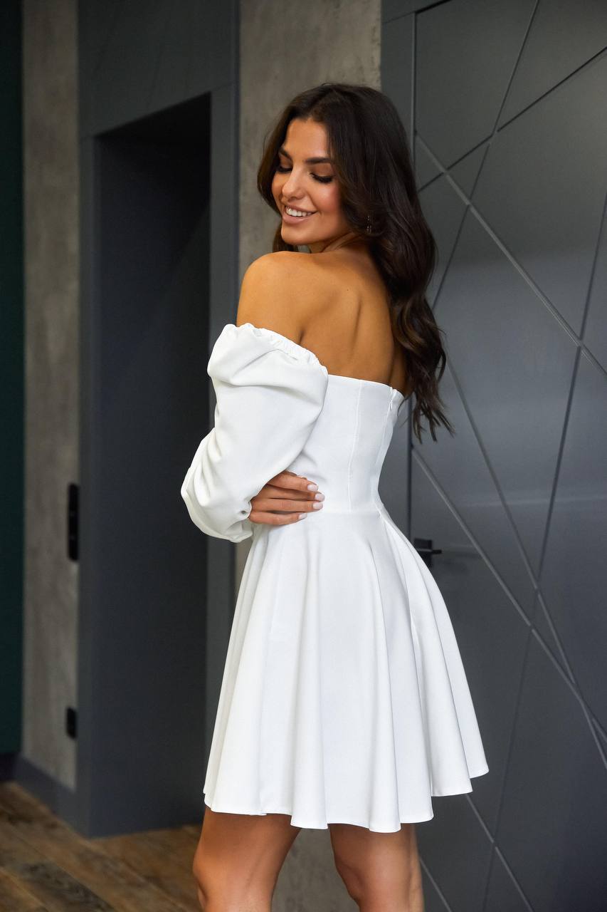 Woman wearing a white dress with a gray wall background