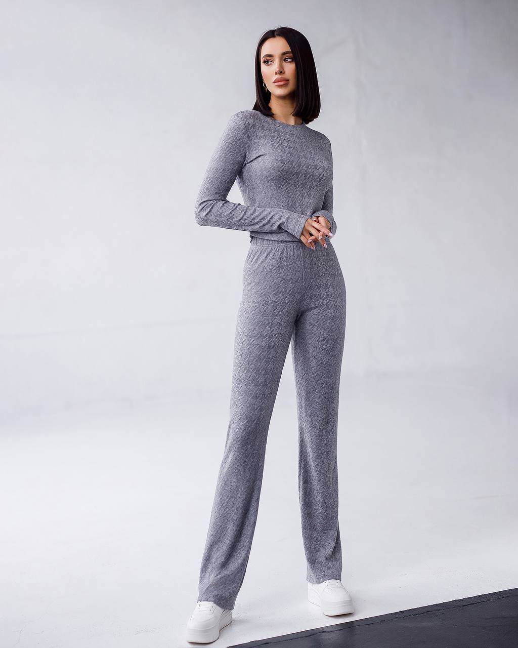 Woman wearing a gray knit outfit on a white background