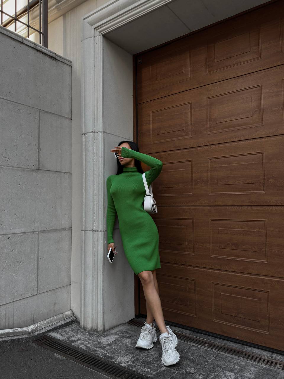 Woman in a green dress standing next to a wooden door