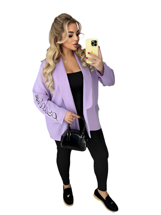 Woman wearing a light purple jacket with text, taking a selfie on a white background
