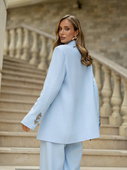 Woman in a light blue suit standing on stone steps with a classical building background