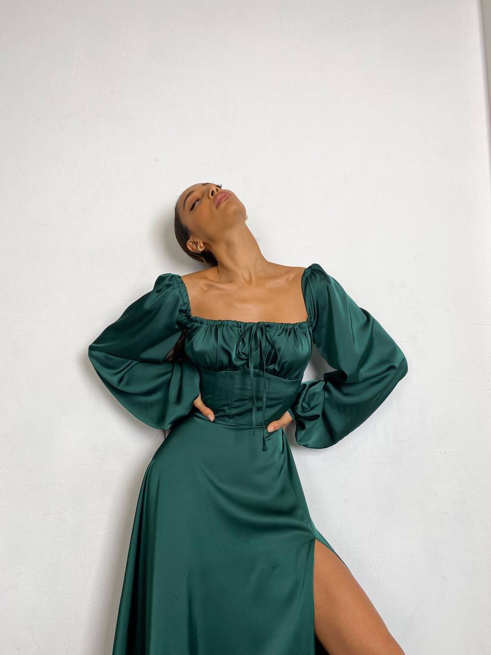 Woman wearing a green dress with long sleeves against a white background