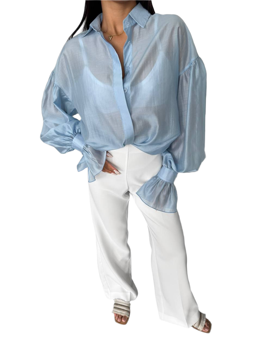 Person wearing a light blue sheer blouse with white pants on a white background