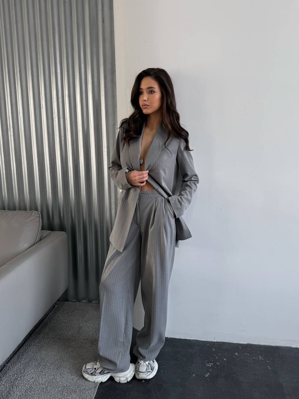 Woman in a gray outfit standing in a modern interior setting.