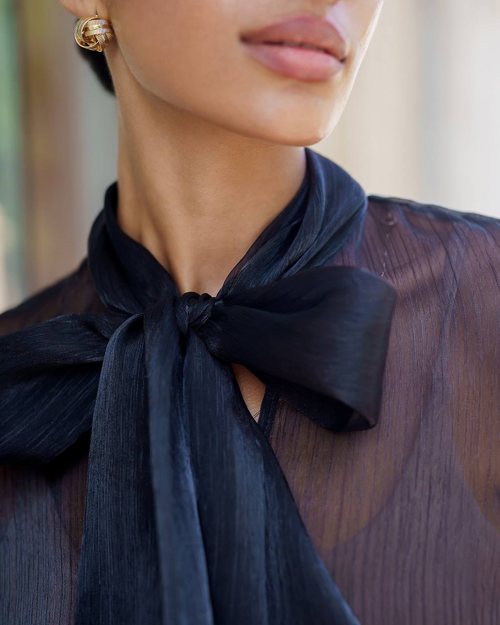 Close-up of a person wearing a dark blue scarf with a bow, blurred background