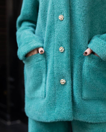 Teal coat with decorative buttons on a dark background