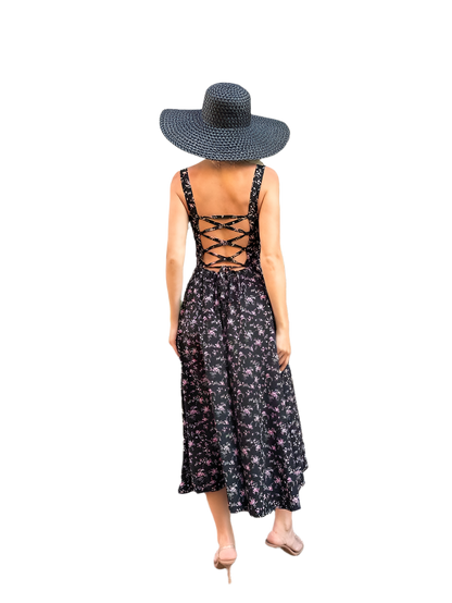 Woman wearing a black floral dress with lace-up back and a wide-brimmed hat on a white background