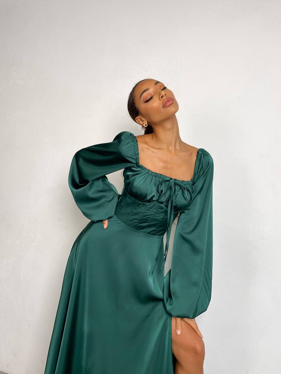 Woman wearing a green dress with puffed sleeves against a white background