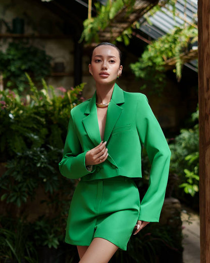 Woman in a green suit standing in a garden setting
