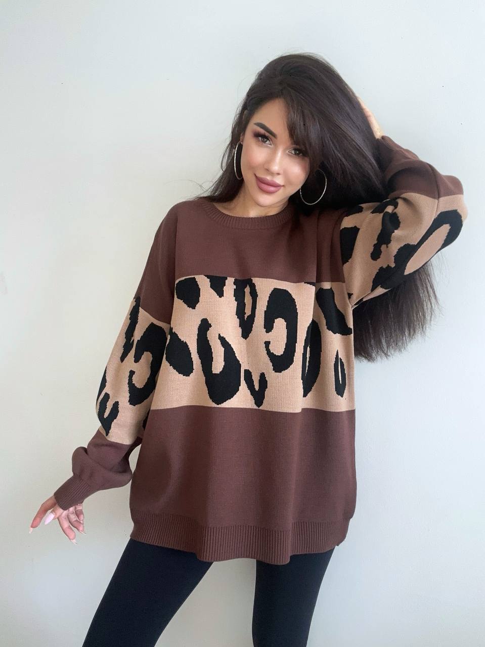 Woman wearing a brown sweater with a leopard print design against a white background