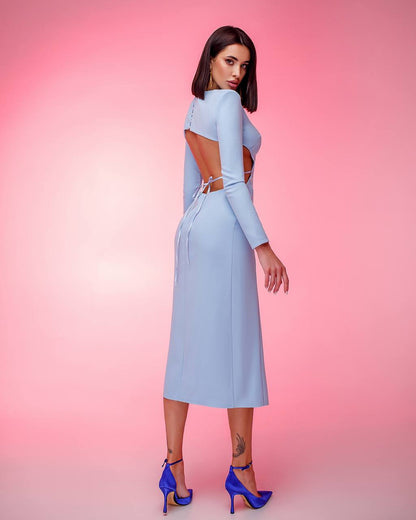 Woman wearing a light blue dress with cut-out design on a pink background