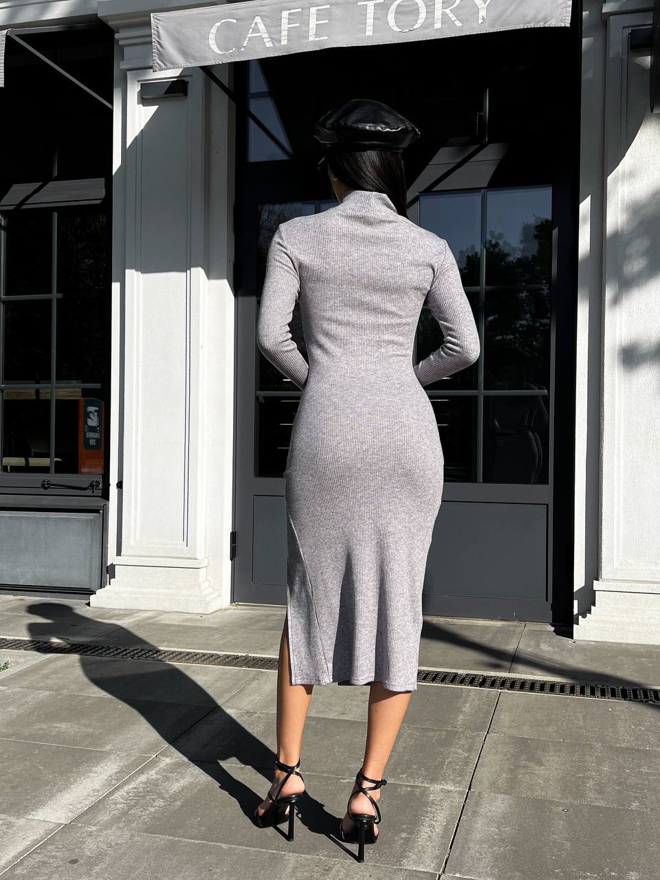 Woman in a gray dress standing outside a cafe named 'Cafe Tory'.