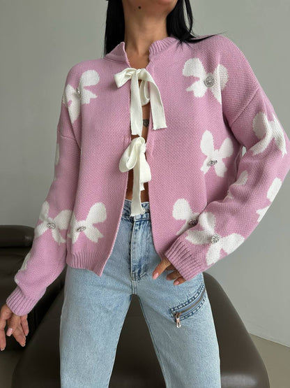 Person wearing a pink sweater with white floral patterns and light blue jeans.