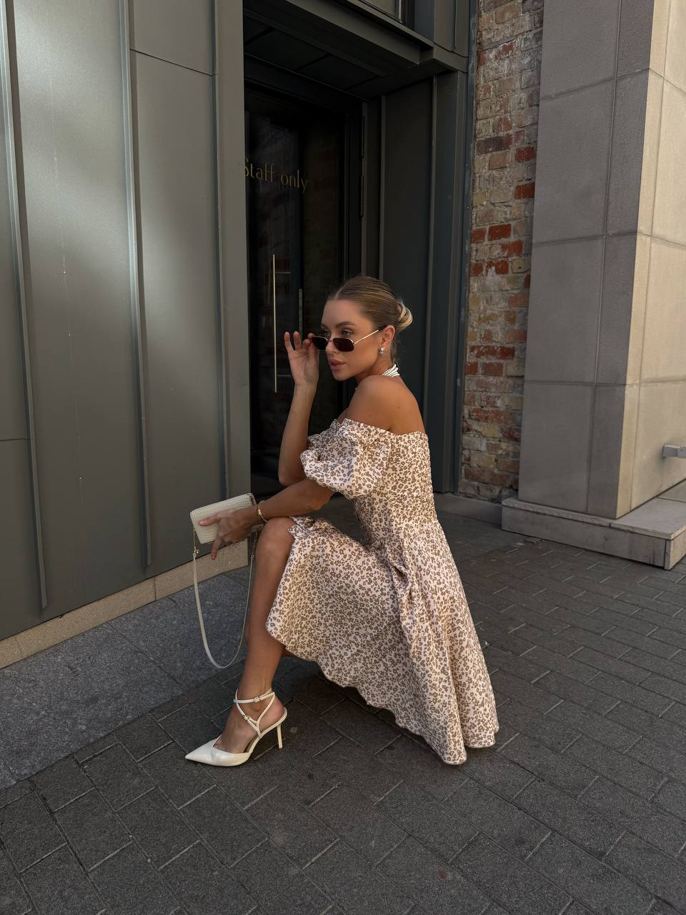 Woman in a floral dress sitting on a step outside a building.