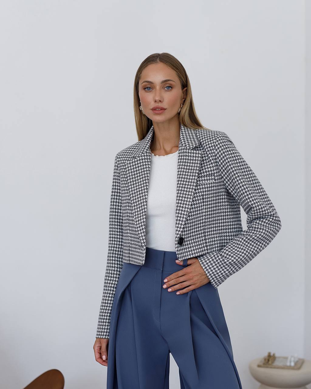 Woman wearing a checkered blazer and blue pants against a white background