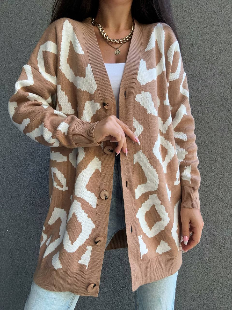 Person wearing a brown cardigan with white abstract pattern against a gray background