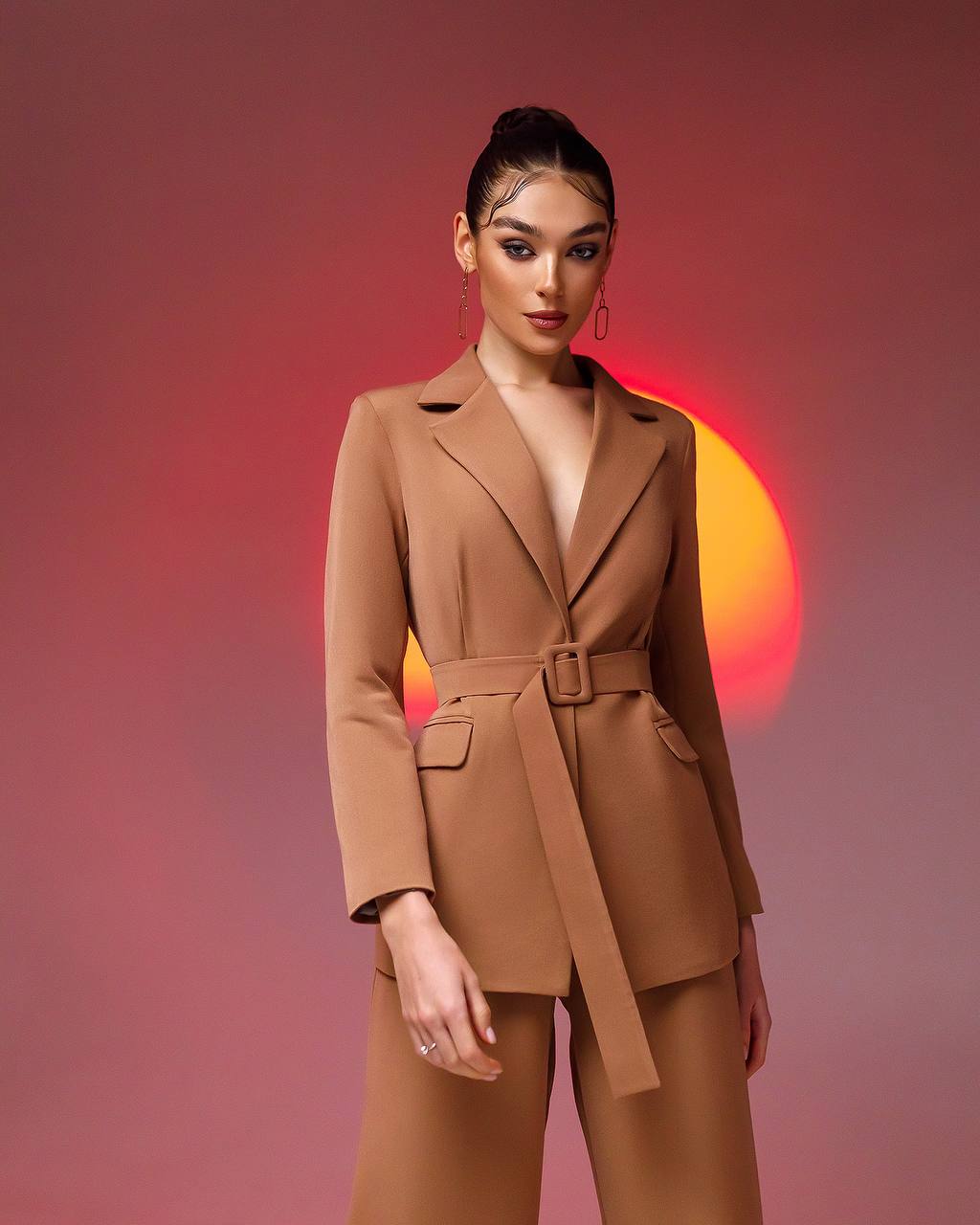 Woman wearing a brown suit with a red and orange gradient background