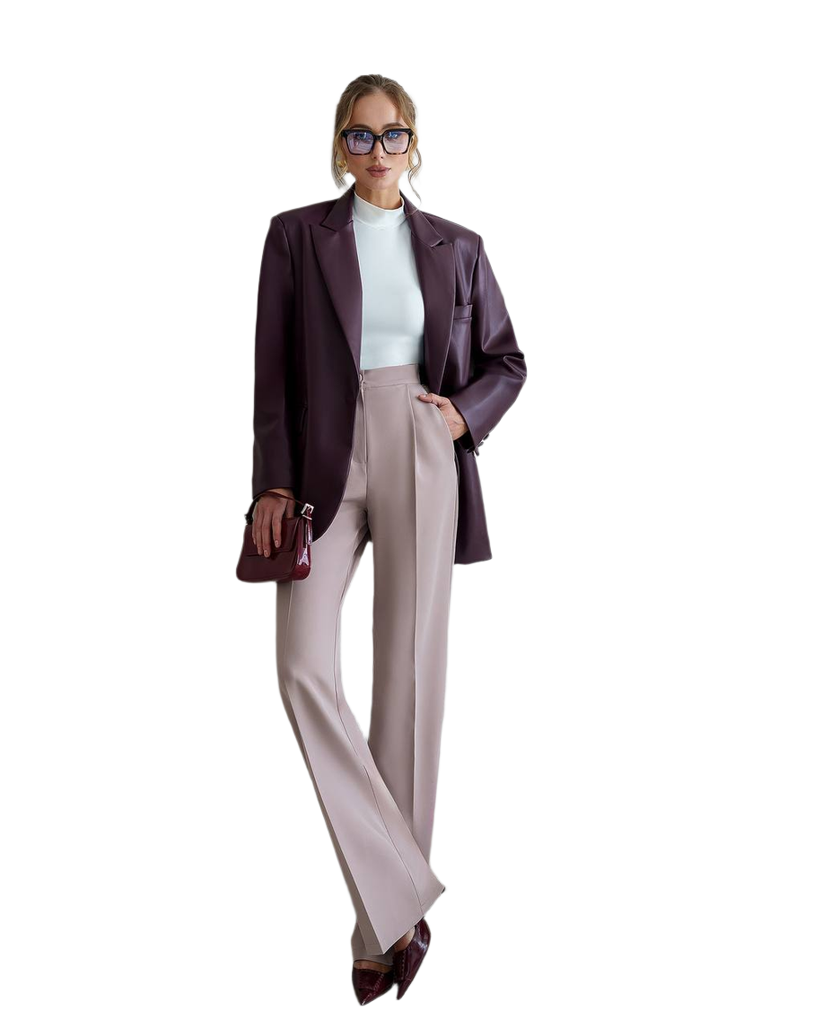 Woman wearing a dark blazer, light shirt, and beige pants on a white background
