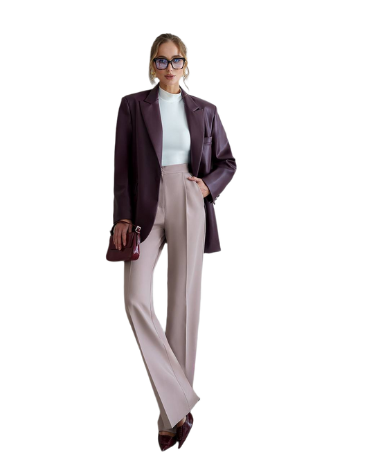 Woman wearing a dark blazer, light shirt, and beige pants on a white background
