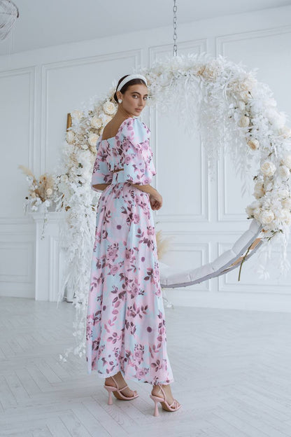 Woman in a floral dress standing in front of a decorative floral arch.