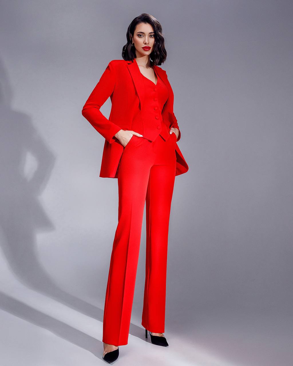 Woman wearing a red suit against a gray background
