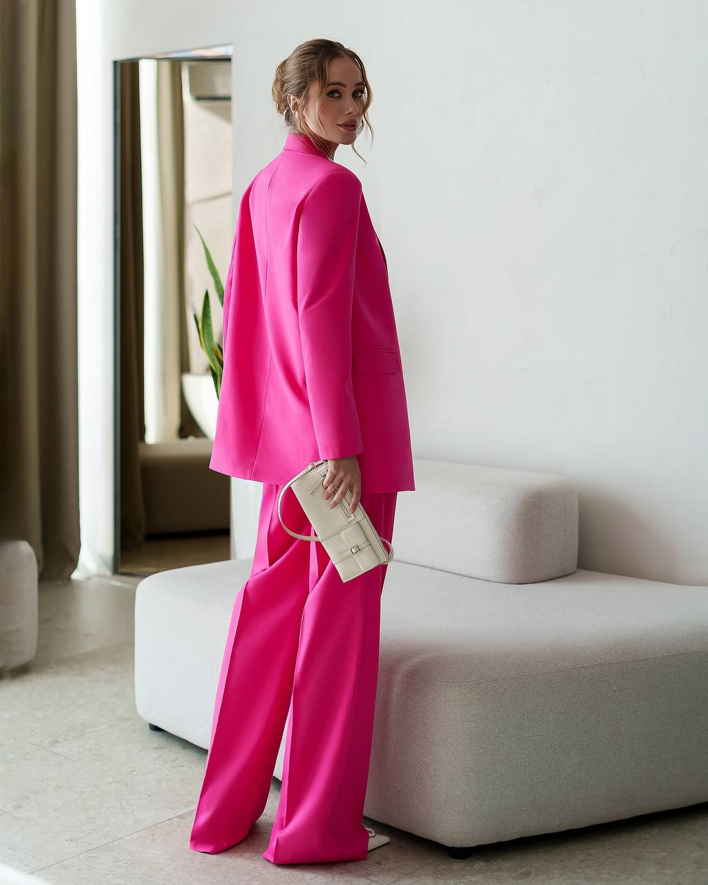 Woman in a bright pink outfit standing in a modern room.