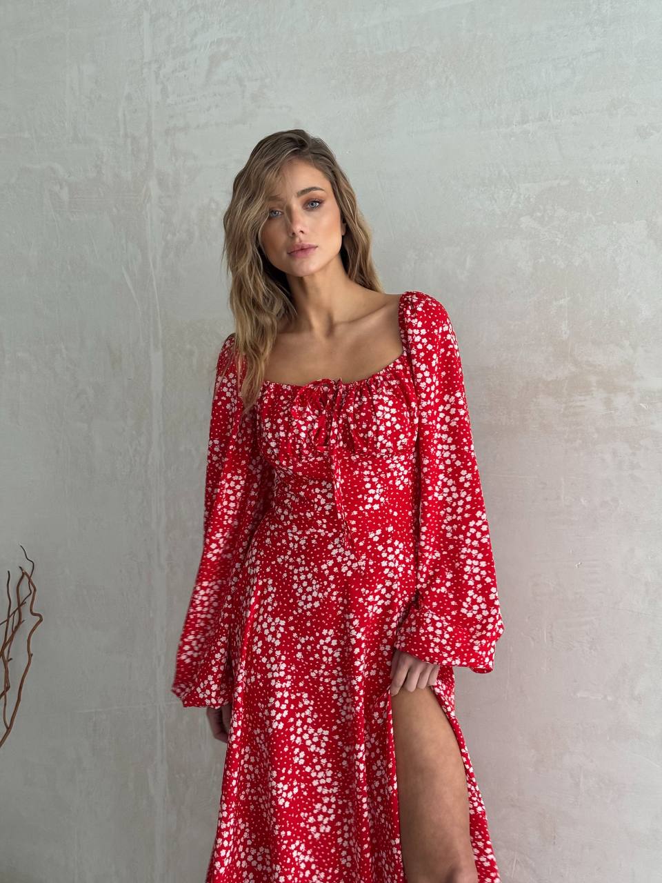 Woman wearing a red floral dress against a plain background